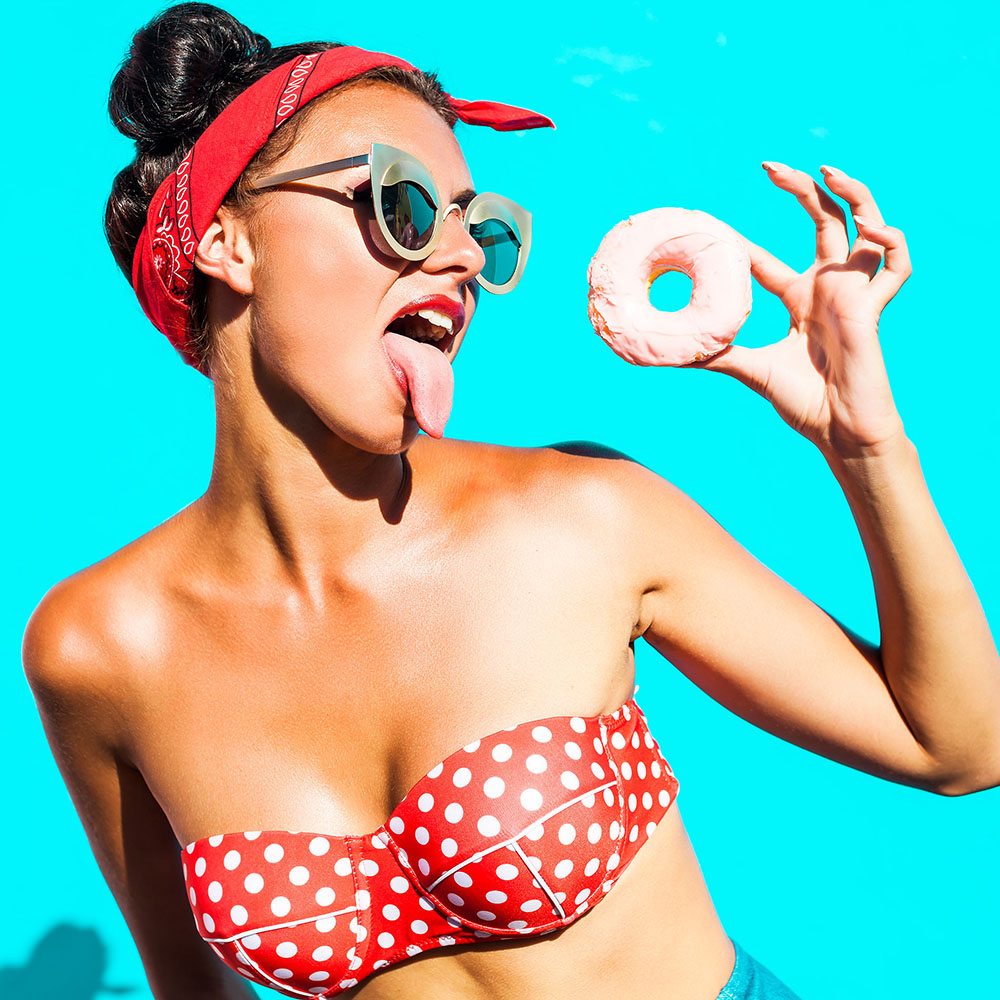 Beautiful, funny, cheerful,  tanned girl eats a sweet donut glaz